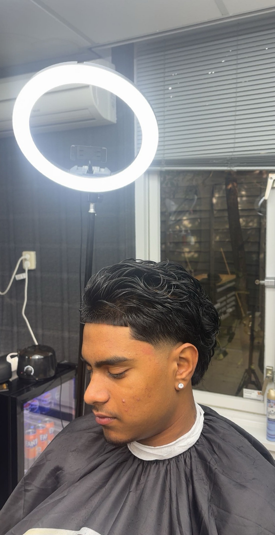 Klant met lang haar bovenop en kort opzij, naast de ringlamp